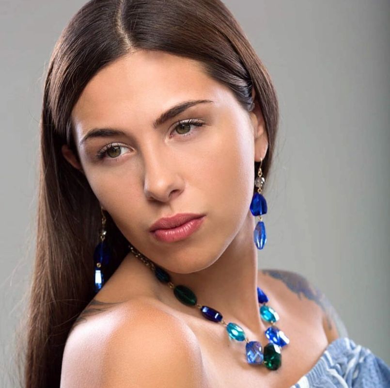 A women with black hair wearing blue colored jewelry