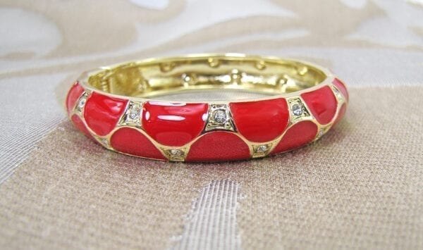 golden bracelet with large red circular inlays on a cloth surface