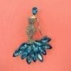 brooch shaped like a woman with blue gems on a red cloth surface