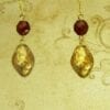 earrings with gold gems and red beads in front of a yellow cloth