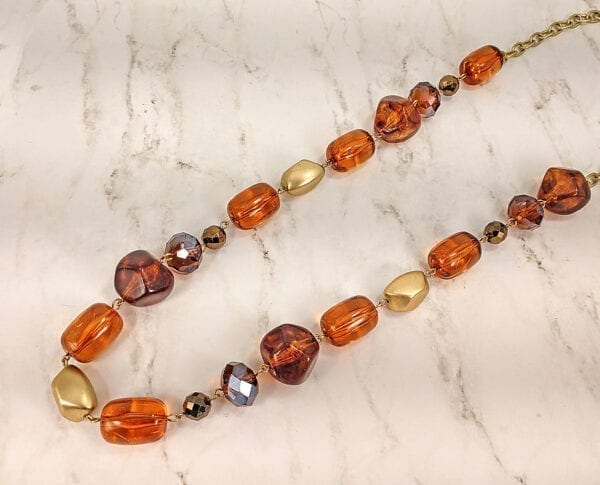 necklace with deep orange pebble stones on a marble surface
