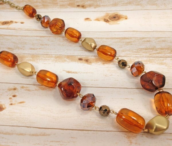 segment of a necklace with deep orange pebble stones on a wooden surface