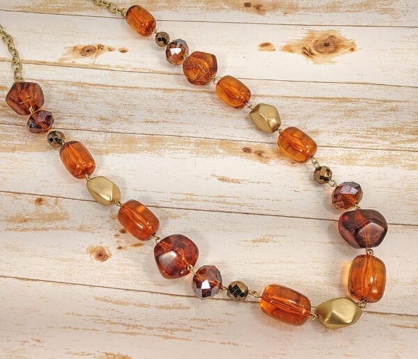 necklace with deep orange pebble stones on a wooden surface