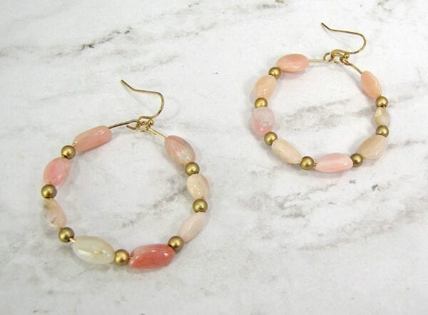 pair of earrings with rows of pink beads on a marble surface