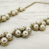 gold necklace with pearls arranged like flowers on a marble surface