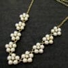 gold necklace with pearls arranged like flowers on a black velvet surface