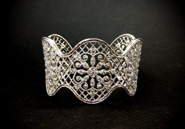 silver bangle with elaborate floral design on a black surface