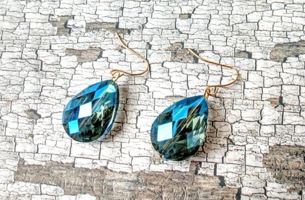 earrings with dark blue teardrop gem on a cracked leather surface