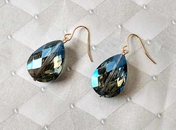 earrings with dark blue teardrop gem on a quilted surface