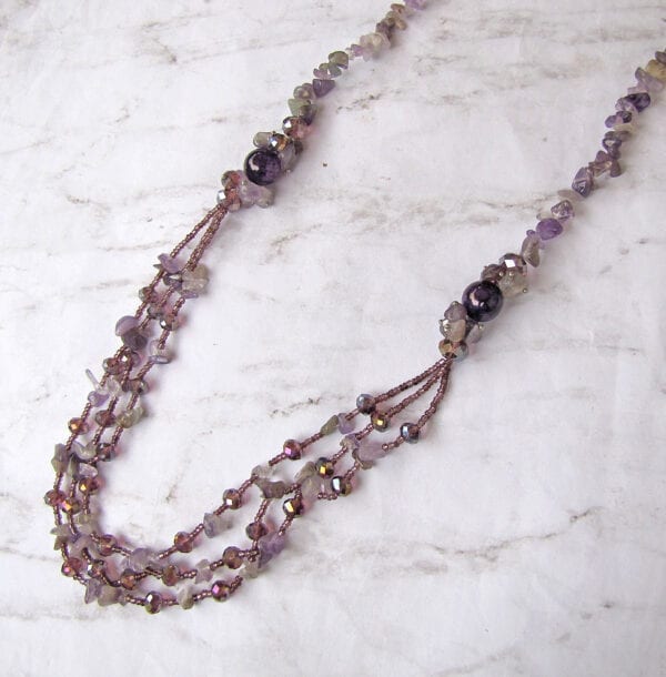 necklace with assorted violet and pink beads on a marble surface