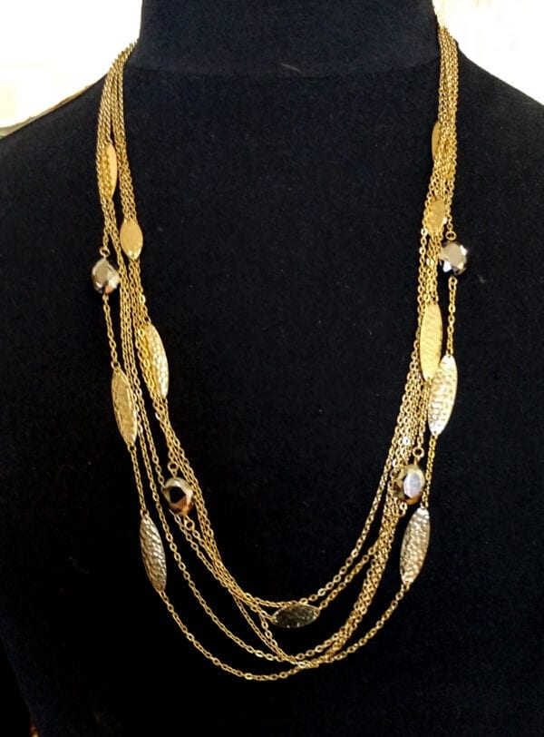 layered necklace with gold chains and large gold bands on a black mannequin