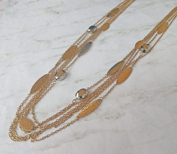 layered necklace with gold chains and large gold bands on a marble surface