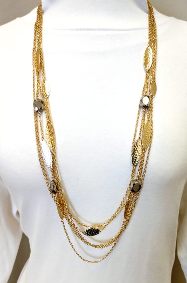 layered necklace with gold chains and large gold bands on a white mannequin
