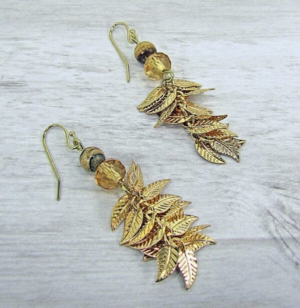 golden earrings with gold leaves on a wooden surface