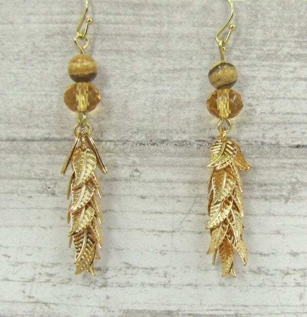 golden earrings with bunch of gold leaves on a wooden surface