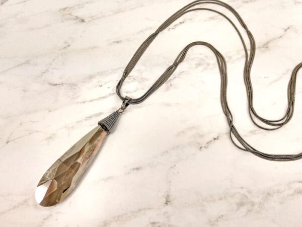 necklace with elongated brown crystal on a marble surface