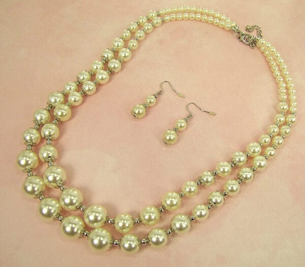 pearl earrings and necklace on a light pink surface