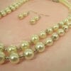 pearl earrings and layered necklace on a light pink surface