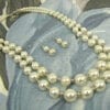 pearl earrings and necklace on a gray cloth surface
