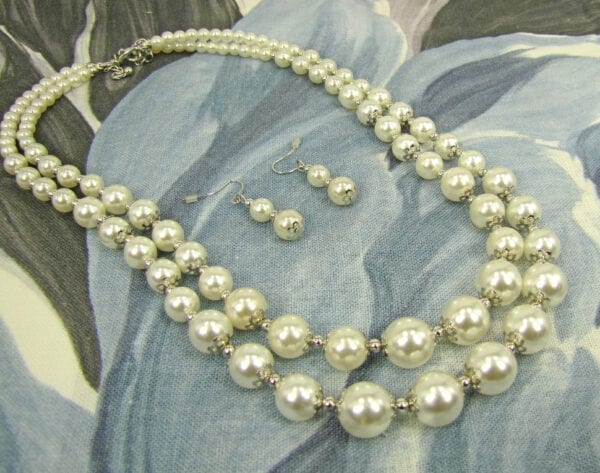 pearl earrings and necklace on a gray cloth surface