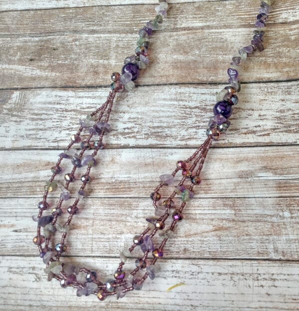 necklace with assorted violet and pink beads on a wooden surface