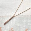 golden bar necklace encrusted with diamonds on a cloth surface