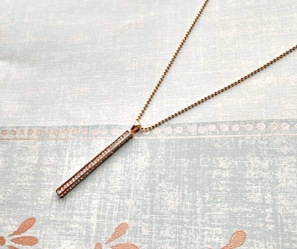 golden bar necklace encrusted with diamonds on a cloth surface