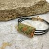 bracelet with large green rectangular pendant on a concrete surface