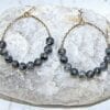 hoop earrings with spherical black crystals on a rock