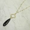 necklace with black, elongated teardrop gemstone on marble surface