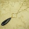 necklace with black, elongated teardrop gemstone on a dark brown surface