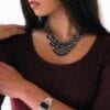 woman wearing layered necklace and earrings with dark circular crystals