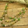 earrings and layered necklace with green and yellow gems on a wooden surface