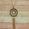 necklace with concentric pendants and brown tassel on a cloth surface