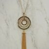 necklace with concentric pendants and brown tassel on a marble surface