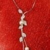 necklace with cascading leaf design and pearl and silver gems on a red fibrous surface