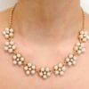 gold necklace with pearls arranged like flowers on a person's neck