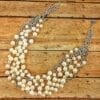 pearl necklace with silver chains on a wooden surface