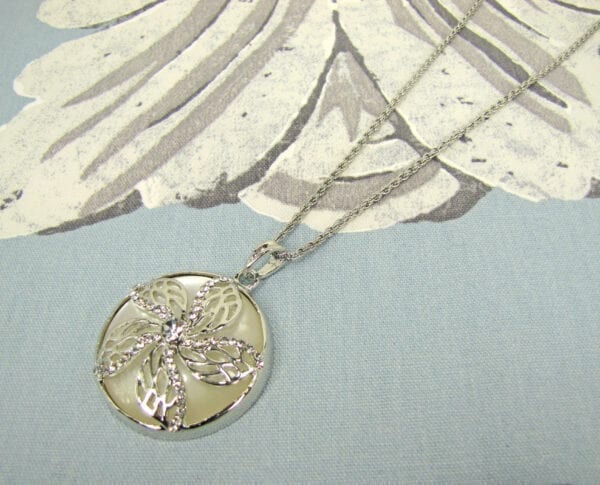 necklace pendant with jade inset and floral metal casing on gray cloth surface