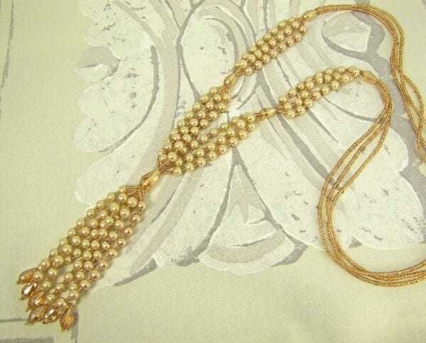 knotted golden necklace with pearl inlays on a fabric surface