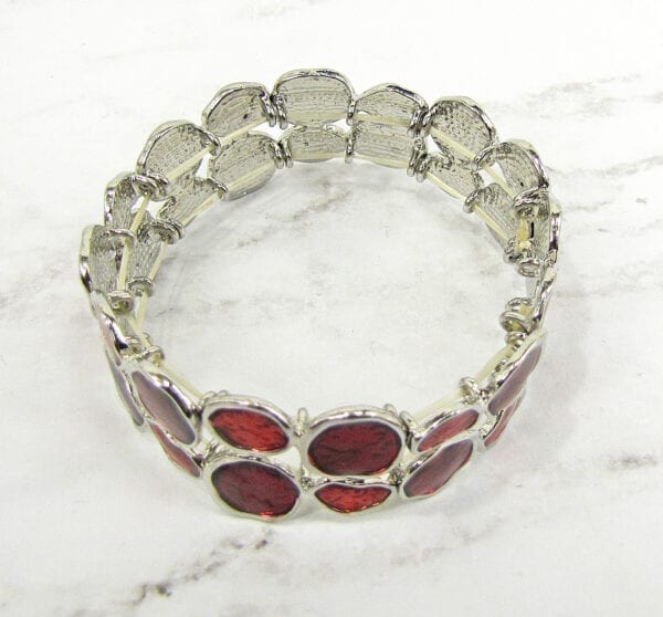 top view of a bracelet with deep red crystal inset on marble surface
