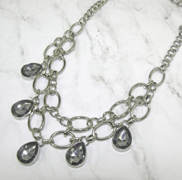 necklace with silver chain links and smoky gray gems on a marble surface