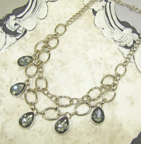 necklace with silver chain links and smoky gray gems on a cloth surface