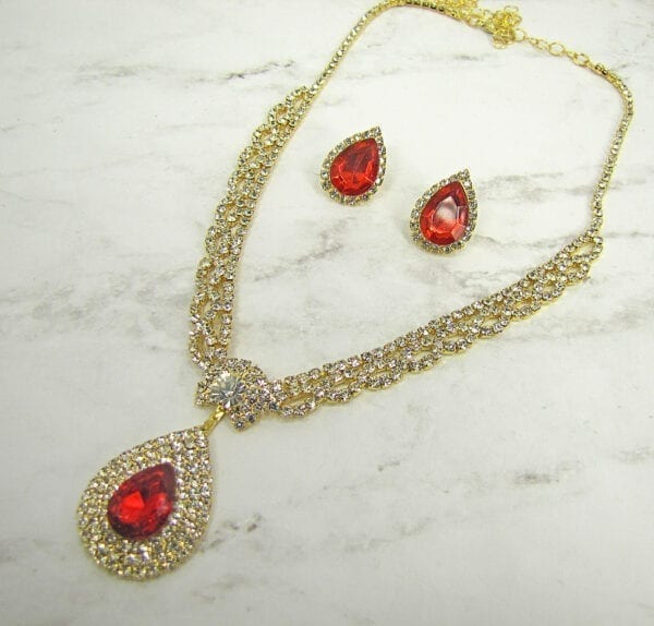 earrings and necklace with large ruby gemstones on a marble surface