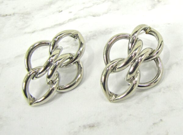 earrings with intertwined and folded golden rings on a marble surface