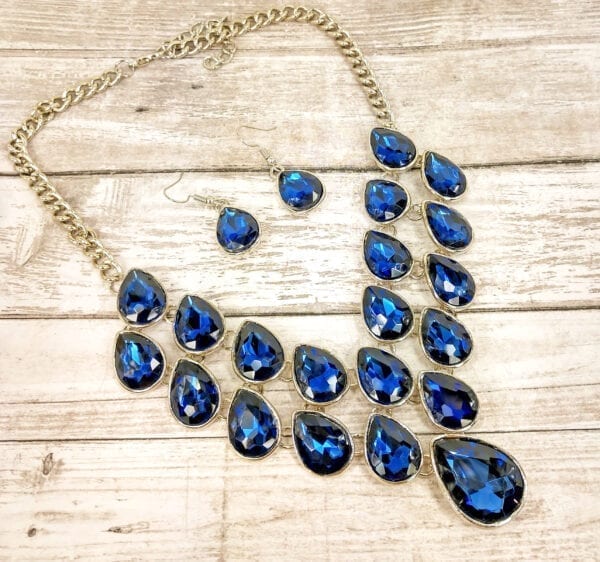 silver chain necklace with many blue teardrop sapphires on a wooden surface