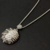 necklace with silver pendant with wing segment design on a black surface