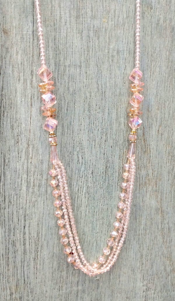 layered necklace with pink crystals on a wooden surface