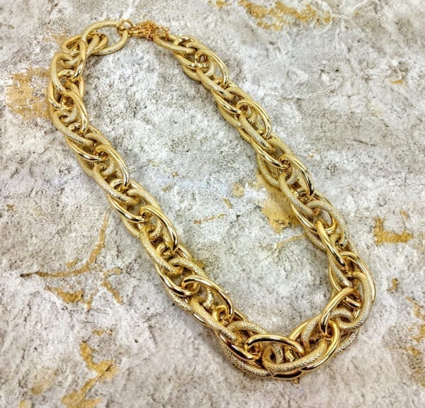 golden necklace with layers of gold chain links on a concrete surface