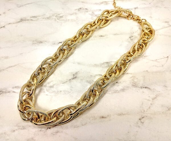 golden necklace with layers of gold chain links on a marble surface